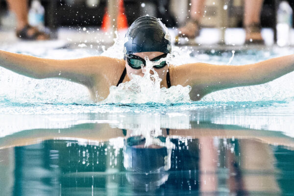 A young swimmer with arms wide above the water competing in butterfly