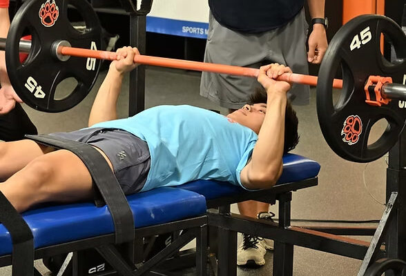 A participant performing a bench press as part of the Dairyland Sports Fitness Foundations program