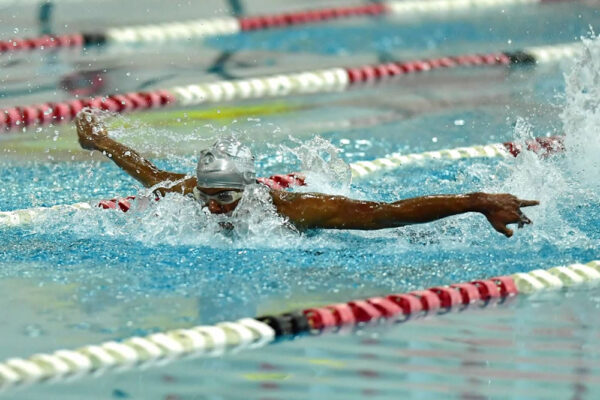 A young swimmer with arms wide above the water competing in butterfly